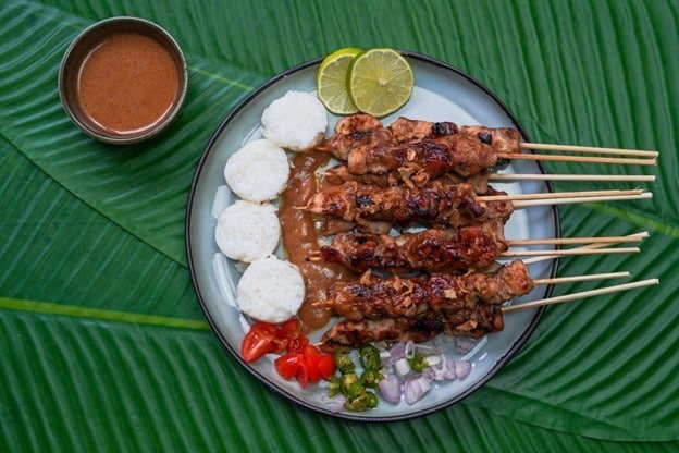 Seporsi sate ayam beserta pelengkapnya di atas piring. Seporsi sate ayam beserta pelengkapnya di atas piring.
